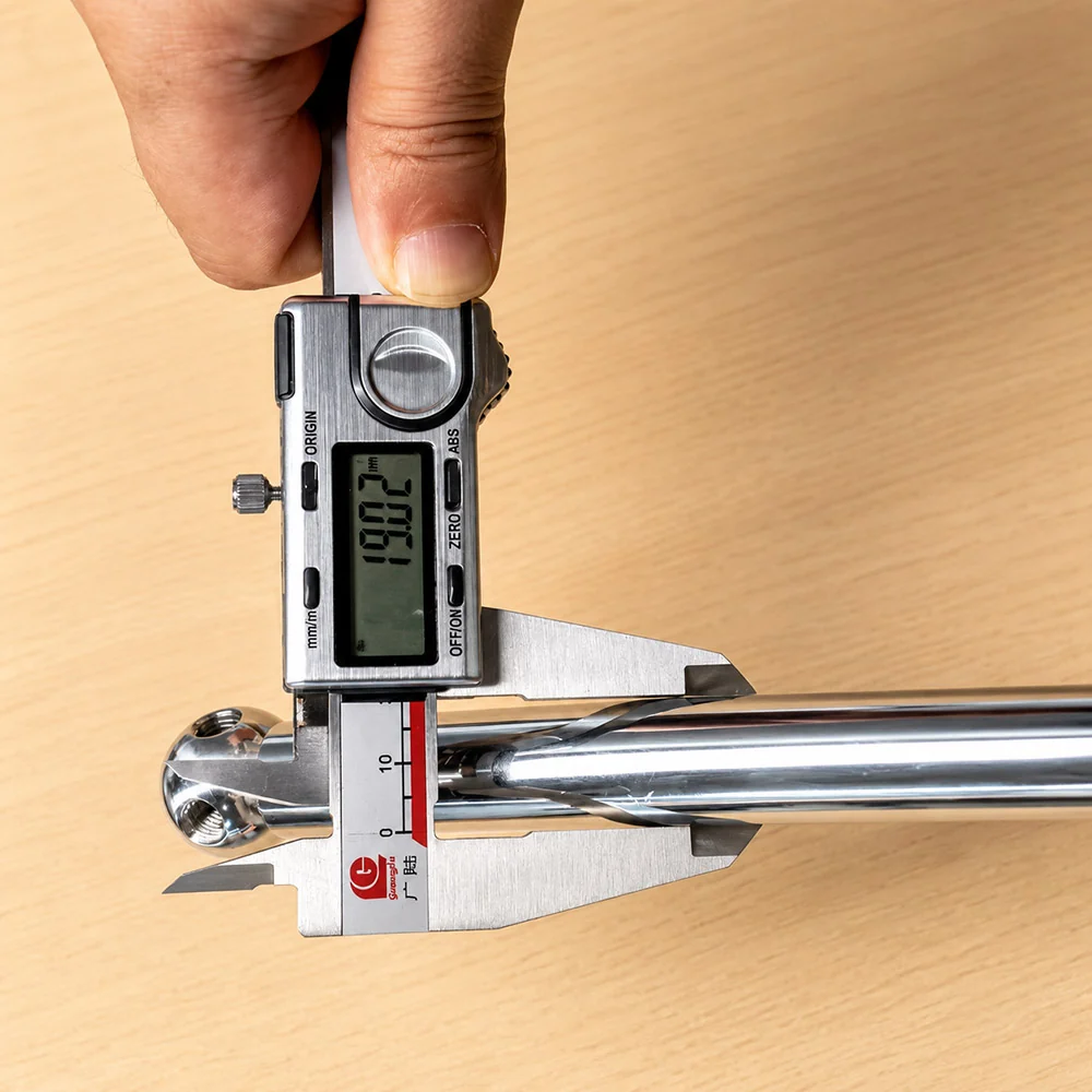 digital caliper measuring a metal furniture component during quality inspection